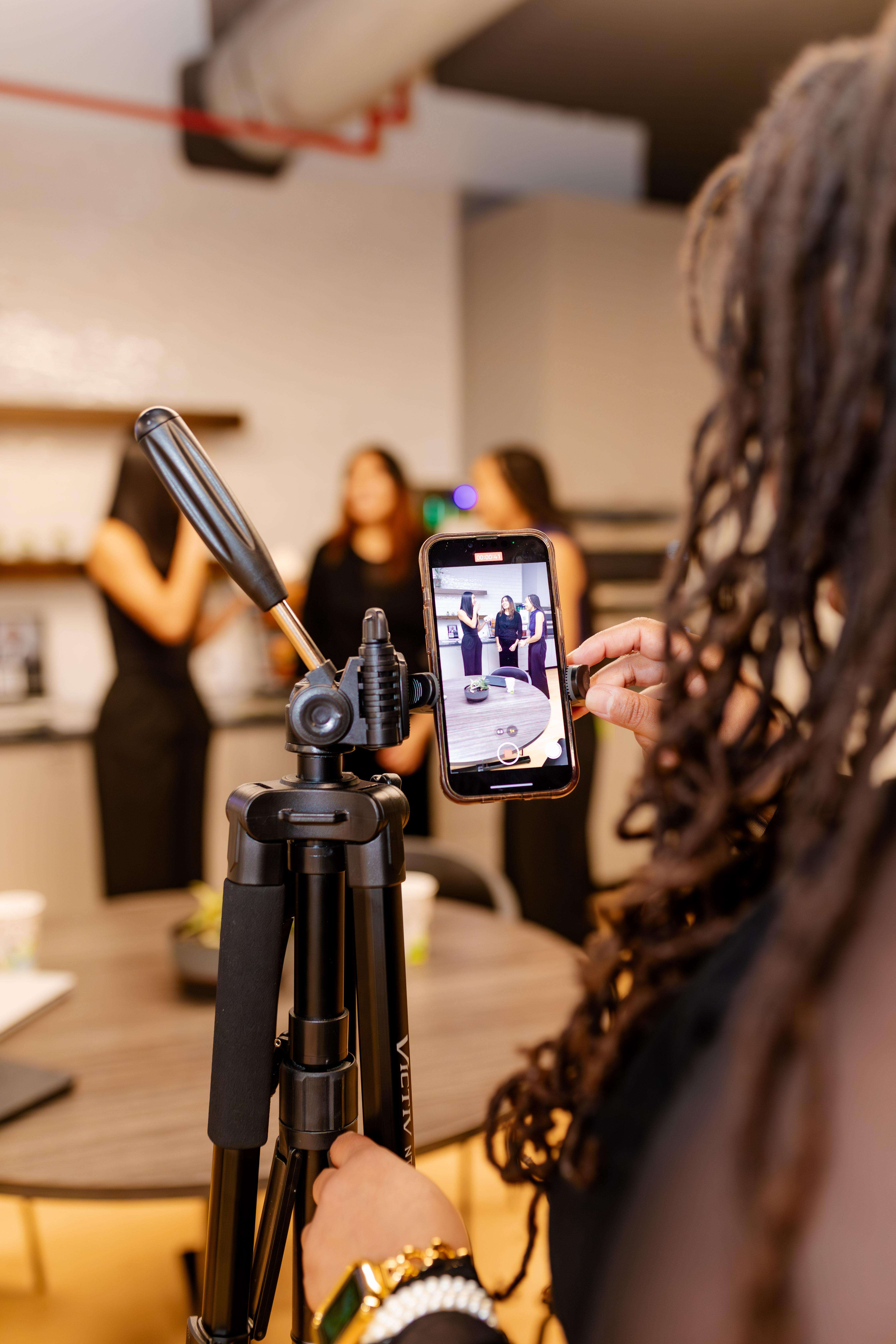 A Peachtree Rose Marketing team member reviews footage on a phone tripod during a content shoot in the San Antonio studio