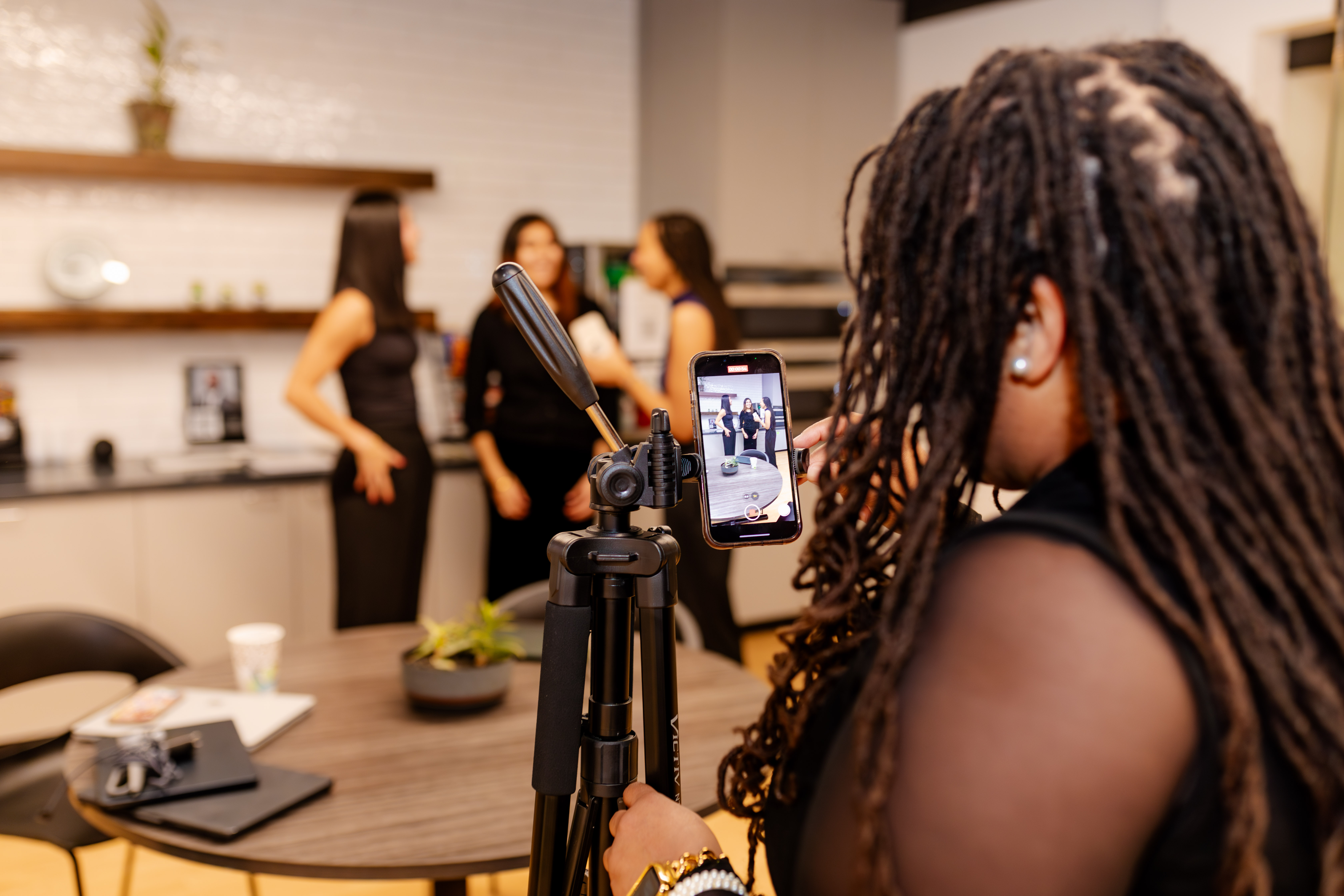 A Peachtree Rose Marketing team member films short-form video on a phone tripod while colleagues talk on camera in the San Antonio studio