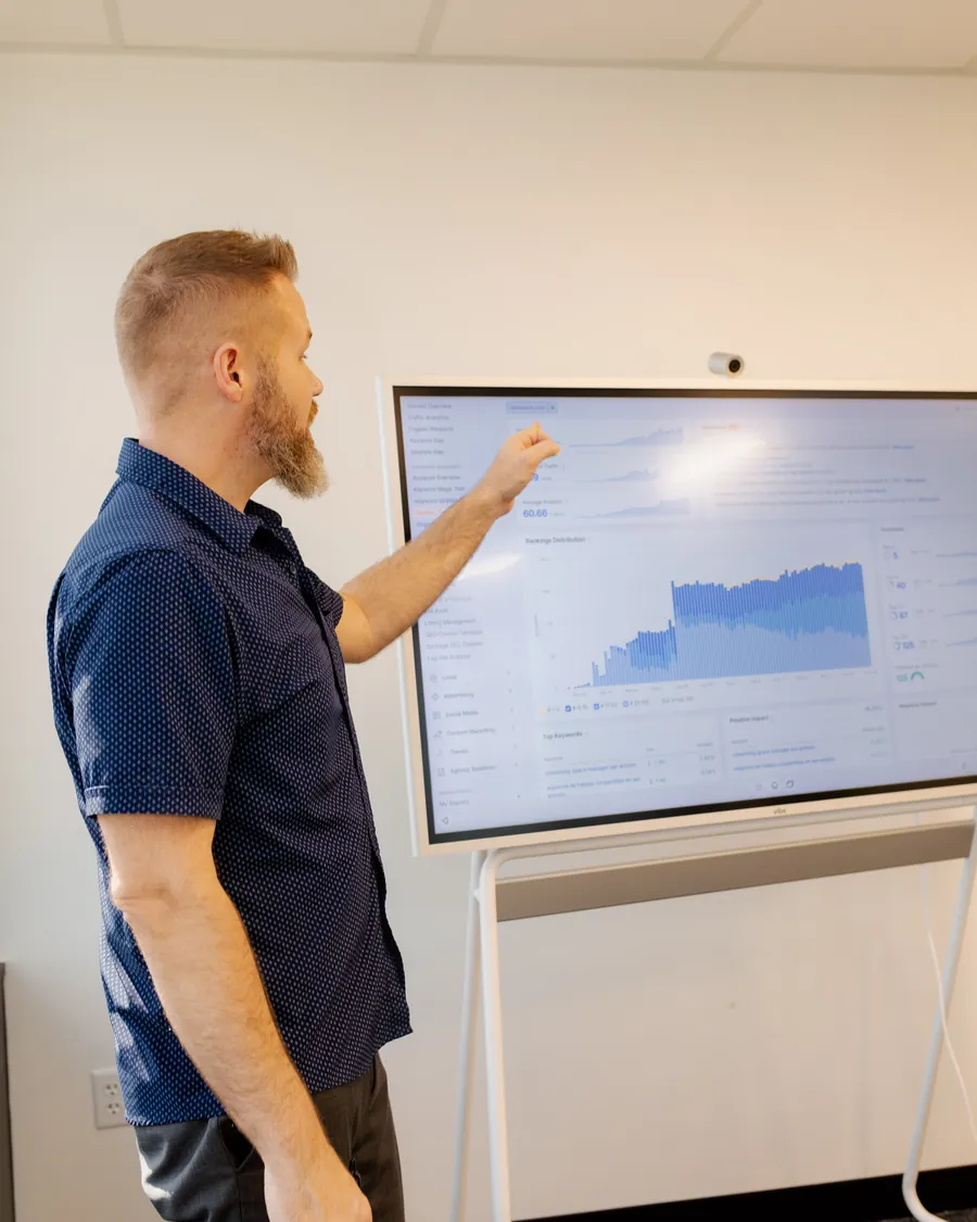 Matt Nelson reviews a search visibility dashboard with rankings data on a large touchscreen.